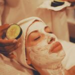 Woman enjoying a spa facial treatment with a soothing cucumber on her face.
