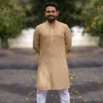 Portrait of a smiling man in a traditional kurta pyjama on a sunny day.