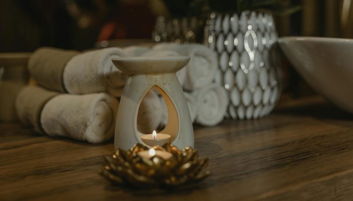 Serene spa setting with a lit candle, ceramic holder, and plush towels for relaxation.